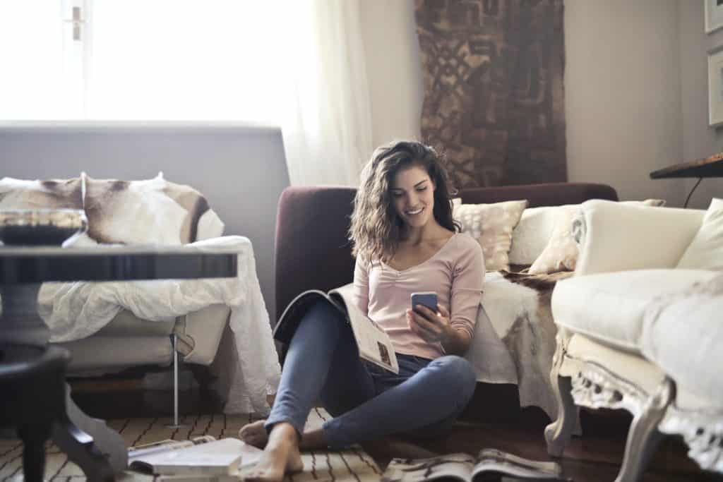 woman reading magazine while on her smart phone